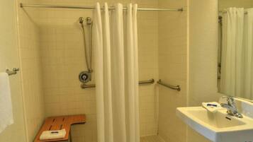 A bathroom with a shower, a sink, and a wooden chair.