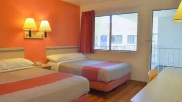A hotel room with two beds, a desk, and a window with curtains.