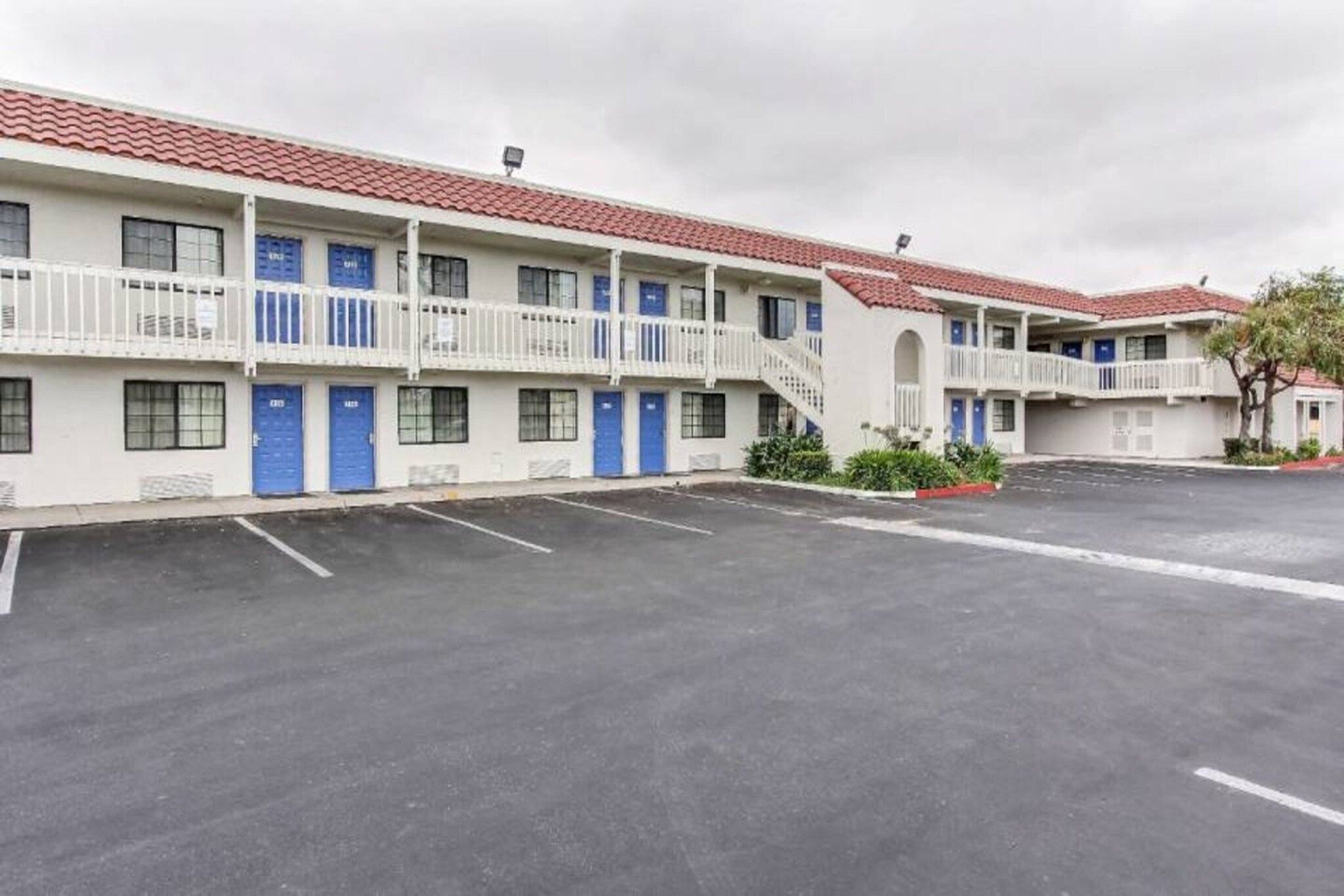 A motel with multiple rooms, a parking lot, and a red-tiled roof.