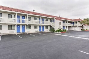 Um motel com vários quartos, estacionamento e telhado de telhas vermelhas.