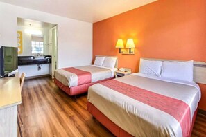 A hotel room with two beds, a desk, a television, and a bathroom visible through an open door.