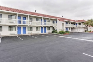 Een motel met meerdere kamers, een parkeerplaats en een dak met rode tegels.