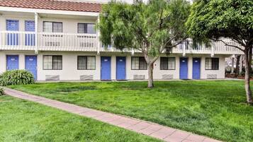 Un edificio con varias puertas azules, un sendero empedrado y césped verde.