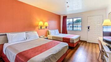Een hotelkamer met twee bedden, een bureau, een stoel, een raam met uitzicht en een deur.