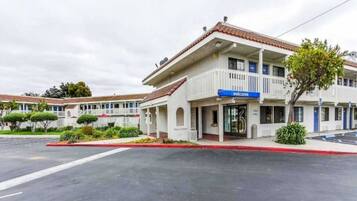 A two-story motel with a 'welcome' sign, a covered parking area, and a red curb.