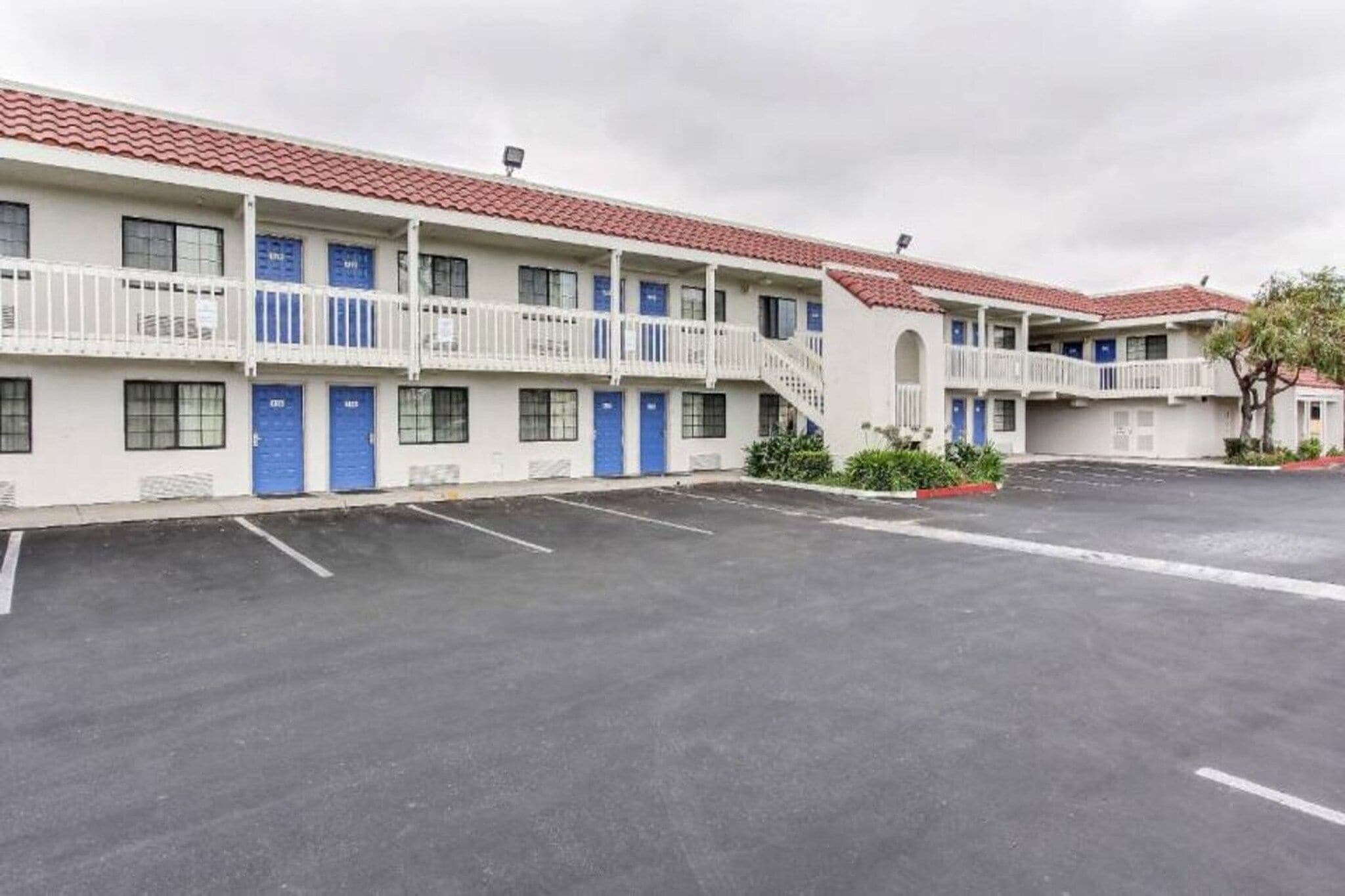 Um motel com vários quartos, estacionamento e telhado de telhas vermelhas.