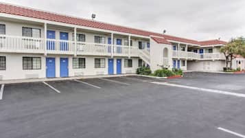 Um motel com vários quartos, estacionamento e telhado de telhas vermelhas.