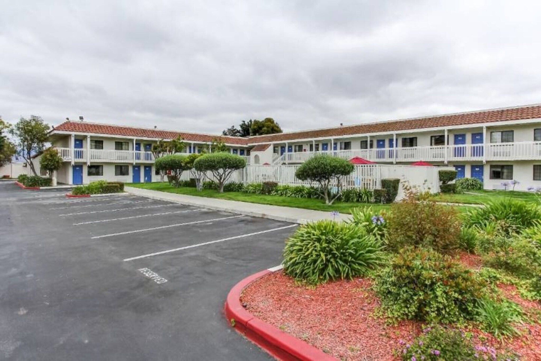 A motel with a parking lot, multiple-story buildings, and a well-maintained lawn.