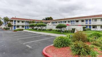 A motel with a parking lot, multiple-story buildings, and a well-maintained lawn.