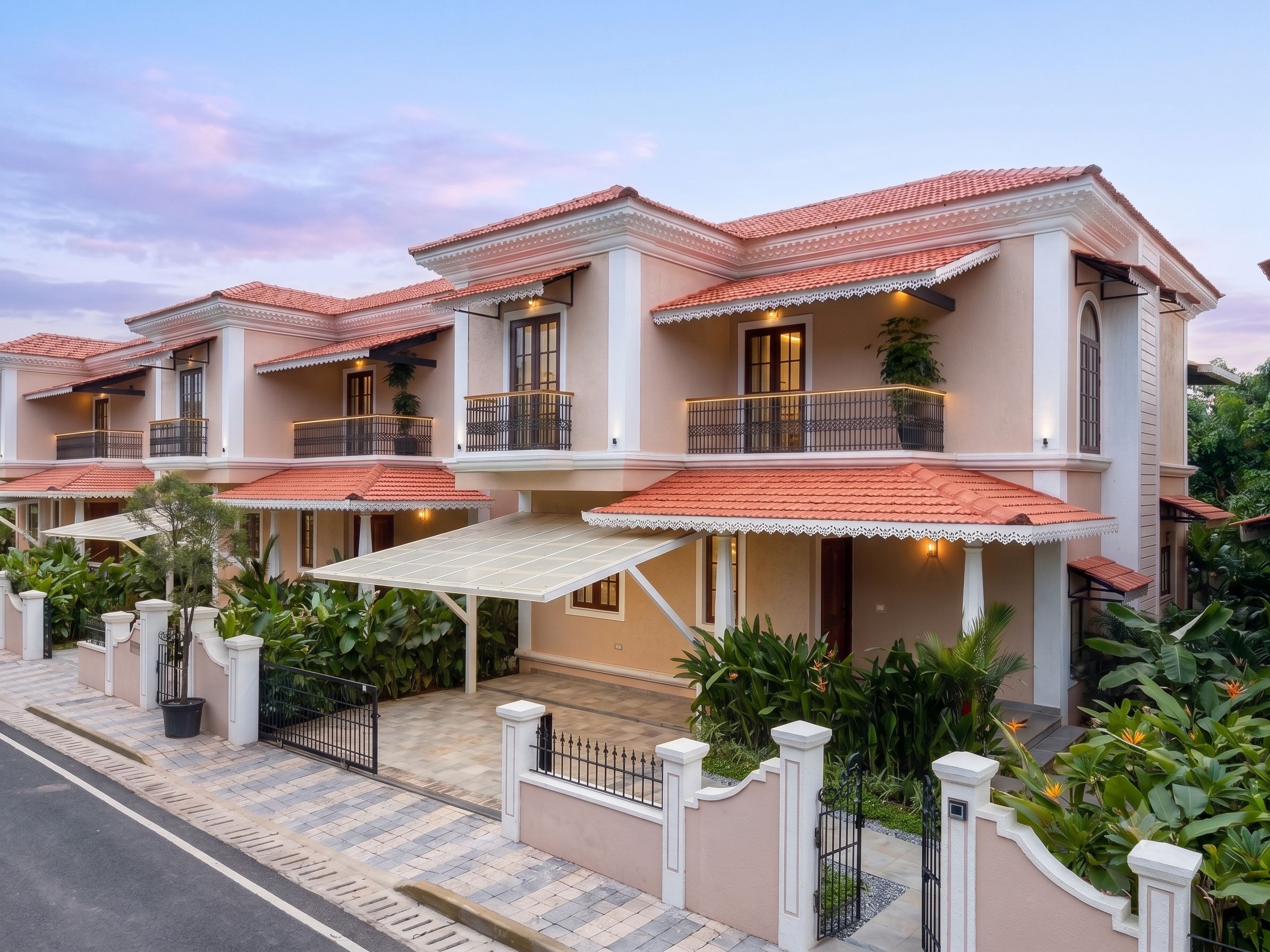 A row of modern houses with red-tiled roofs, balconies, and a gated entrance.