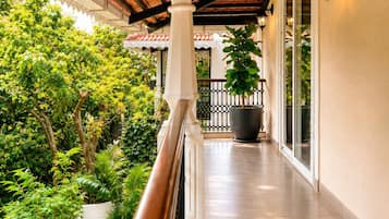 A covered outdoor corridor with a pool, surrounded by greenery and a tiled floor.