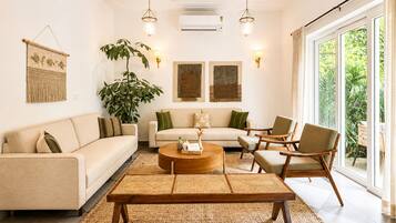 Un salon comprenant un canapé, des fauteuils, une table basse et une grande plante.
