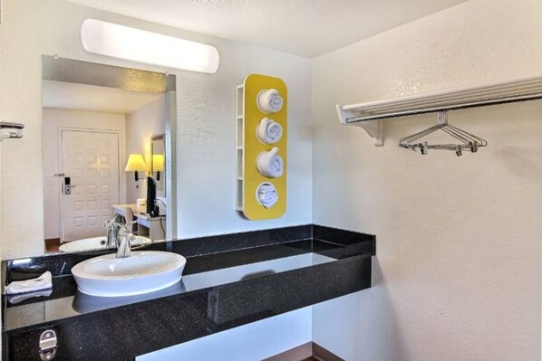 Un baño con lavamanos doble, espejo, toallero y dispensador de toallas.