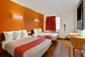 A hotel room with two beds, a desk, and a chair.