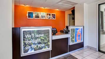 A hotel reception desk with a large sign that reads 'We'll leave the light on for you.'