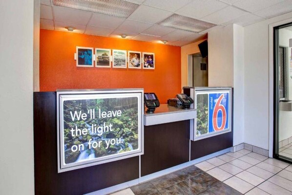 A hotel reception desk with a large sign that reads 'We'll leave the light on for you.'