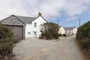 A rural road with houses on either side, gravel driveway, and a clear sky. - Wood Cottage (Wadebridge)