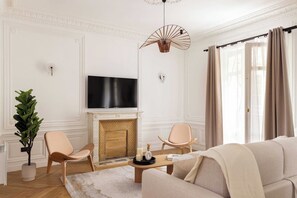 Een woonkamer met een open haard, een televisie en twee stoelen.