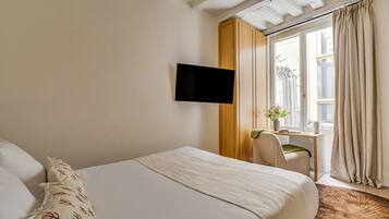 Een hotelkamer met een bed, een bureau met stoel, een televisie en een raam met gordijnen.