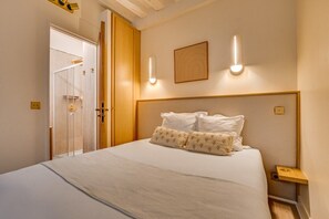 Een hotelkamer met een bed, nachtkastje, wandlamp en een deur.