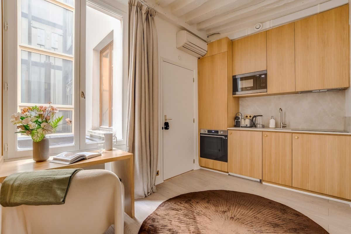Ett kompakt kök med träskåp, en mikrovågsugn och en diskmaskin.