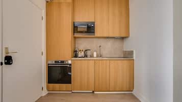 Eine kleine Küche mit Holzschränken, einer Mikrowelle, einem Toaster und einem Backofen.