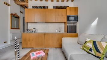 A compact living space with a kitchenette, a sofa, and a coffee table.