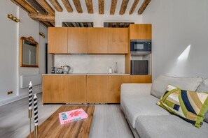 Ein kompakter Wohnbereich mit Küchenzeile, einer Couch und einem Couchtisch.