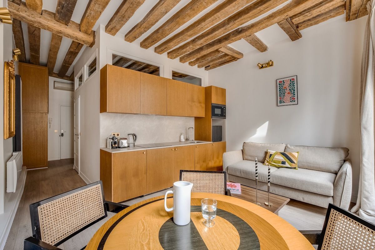 A compact living space with a kitchenette, a dining area with a round table, and a sofa.