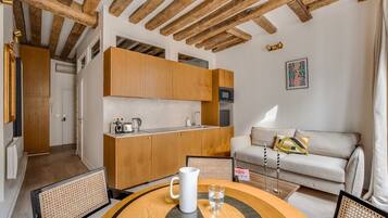 A compact living space with a kitchenette, a dining area with a round table, and a sofa.