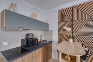 A modern kitchen with a black countertop, stainless steel sink, and a built-in microwave. - Peaceful Studio for a Calm & Soothing Retreat (Paris)