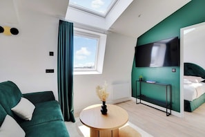 A modern hotel room with a sofa, a round wooden coffee table, a TV, and a bed. - Breathtaking View over Parisian Skyline - Voltaire (Paris)