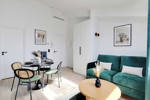 A modern living space with a dining area, a green sofa, and a round coffee table. - Breathtaking View over Parisian Skyline - Voltaire (Paris)