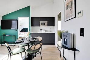 A modern kitchen with a microwave, a dining area with a table set for two, and a bookshelf with a book. - Breathtaking View over Parisian Skyline - Voltaire (Paris)