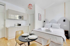 A modern hotel room with a bed, a small kitchenette, and a dining area. - Your Parisian Home Base in the 18th District (Paris)