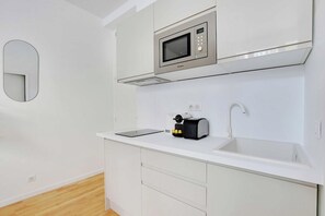 A modern kitchen with a microwave, toaster, and sink. - Your Parisian Home Base in the 18th District (Paris)