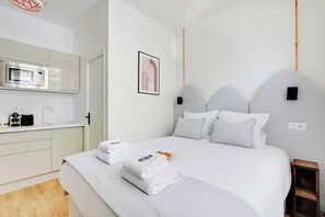 Quarto de hotel com cama, mesa de cabeceira, micro-ondas e um pequeno armário.