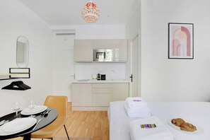 Quarto de hotel com cama, mesa de jantar, cozinha e banheiro.