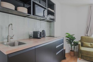 A modern kitchen with a built-in sink, a microwave, and a coffee maker on the countertop. - Clean & Modern Flat near Vibrant Bastille (Paris)