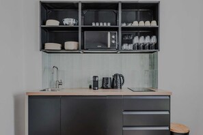 A modern kitchen with a built-in microwave, coffee maker, and kettle on the countertop. - Clean & Modern Flat near Vibrant Bastille (Paris)