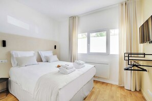 A hotel room with a large bed, a window with curtains, a radiator, and a wall-mounted TV. - Comfortable Cocoon to explore Paris (Paris)