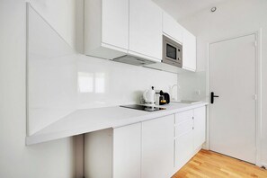 A modern kitchen with white cabinetry, a stainless steel microwave, and a coffee maker on the countertop. - Comfortable Cocoon to explore Paris (Paris)