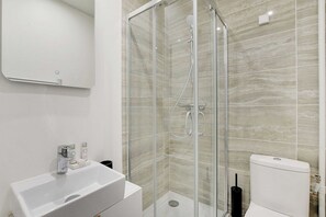 A modern bathroom with a glass-enclosed shower, a white sink, and a toilet. - Comfortable Cocoon to explore Paris (Paris)
