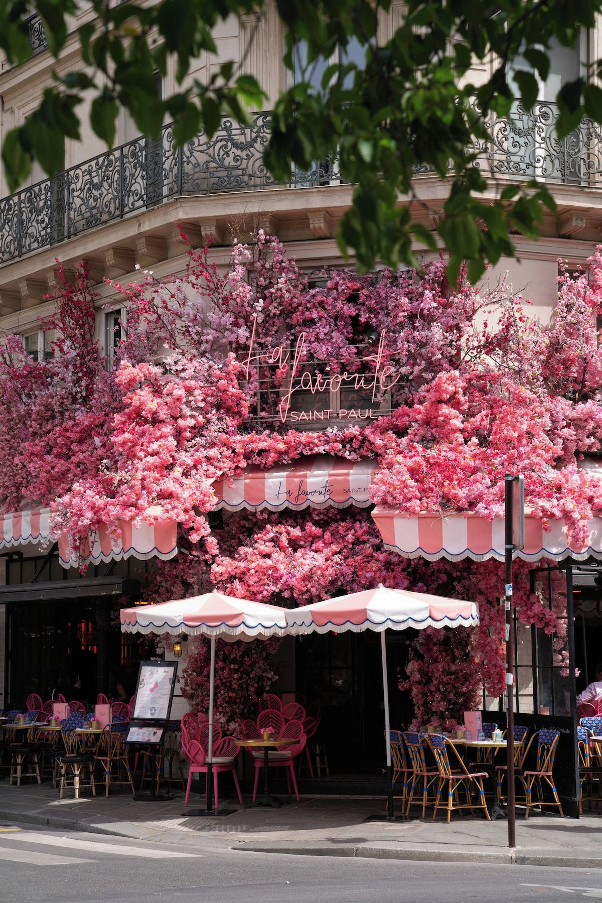 Een café met roze bloemendecoratie en terras.