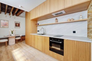 A modern kitchen with wooden cabinets, a built-in oven, and a white countertop. - Parisian Elegance: Modern Flat in Central Paris (Paris)
