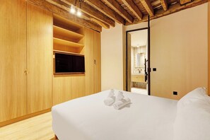 A hotel room with a large bed, wooden wardrobe, and a bathroom visible through an open door. - Parisian Elegance: Modern Flat in Central Paris (Paris)
