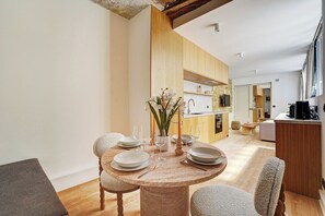 A modern dining area with a round wooden table set for four, surrounded by chairs. - Parisian Elegance: Modern Flat in Central Paris (Paris)