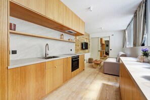 A modern kitchen with wooden cabinets, a built-in oven, and a large window. - Parisian Elegance: Modern Flat in Central Paris (Paris)