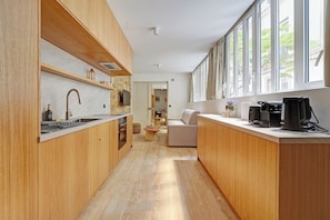A modern kitchen with wooden cabinets, a built-in oven, and a large window providing natural light. - Parisian Elegance: Modern Flat in Central Paris (Paris)