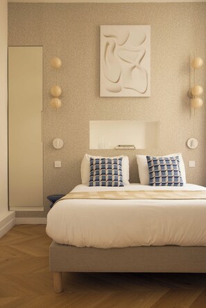 Ein Schlafzimmer mit einem Bett, Kissen, einer Wandleuchte und einer Tür.